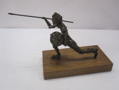 Bronzed-effect abstract figure of warrior with spear and shield, on wooden base, 30cm wide x 19cm