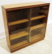 Mid-century modern teak bookcase with shaped sliding glass doors enclosing adjustable shelving, on