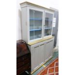 Painted cabinet with moulded corners above two glazed doors enclosing shelves, the painted base of