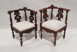 Two similar corner armchairs with heavily carved top rails featuring mask decoration, carved and