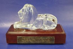 A Steuben art glass model of a recumbent lion designed by Lloyd Atkins, with wooden plinth base, the