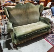 Late 19th/early 20th century wingback two-seat sofa in green upholstery, on turned front legs