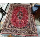 Eastern-style rug with central medallion on a red ground foliate decorated field, navy ground