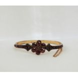 Gold-coloured metal and garnet set bangle having flowerhead to the top with small garnets, claw