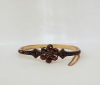 Gold-coloured metal and garnet set bangle having flowerhead to the top with small garnets, claw