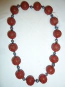 Oriental cinnabar and enamel shou necklace, the large cinnabar beads carved geometric design and