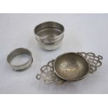 Silver tea strainer with pierced handles, a silver  napkin ring and a small silver bowl, varying