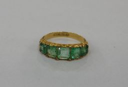 Emerald dress ring set five emerald cut stones interspersed with small old cut diamonds, in scroll