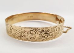 9ct gold hinged bangle with engraved scrolling decoration, approx. 25g