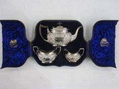 A late Victorian silver three-piece tea service having gadrooned rims, the bodies with repousse