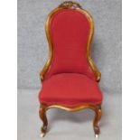 A Victorian carved walnut framed nursing chair in rouge upholstery on cabriole supports. H.94cm