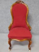 A Victorian carved walnut framed nursing chair in rouge upholstery on cabriole supports. H.94cm