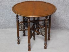 An Eastern folding occasional table with circular lift off oak top. H.54 W.61 D.61cm