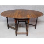 An oak drop flap dining table on stretchered barleytwist supports. H.75 W.150 D.104cm
