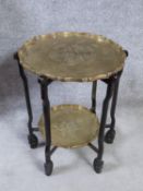 A Chinese hardwood folding occasional table with scalloped edged brass trays with an engraved