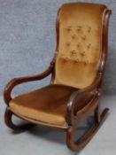 A Victorian mahogany framed 'slipper' rocking armchair in buttoned back upholstery. H.98cm