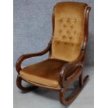 A Victorian mahogany framed 'slipper' rocking armchair in buttoned back upholstery. H.98cm