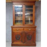 A late Victorian carved walnut library bookcase the upper glazed section above panel doors on plinth