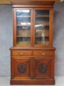 A late Victorian carved walnut library bookcase the upper glazed section above panel doors on plinth