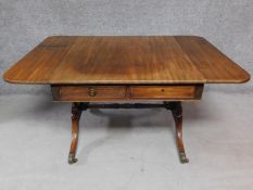 A Regency mahogany sofa table with twin drop flaps on stretchered swept supports terminating in