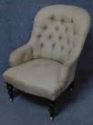 A Victorian upholstered button back armchair on turned tapering walnut supports terminating in brass