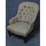 A Victorian upholstered button back armchair on turned tapering walnut supports terminating in brass