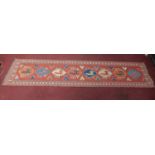 A Kazak style runner, repeating reindeer motifs on a terracotta field within geometric border