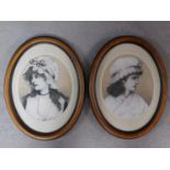 A pair of framed and glazed mixed media artworks depicting two women in Victorian garments, signed