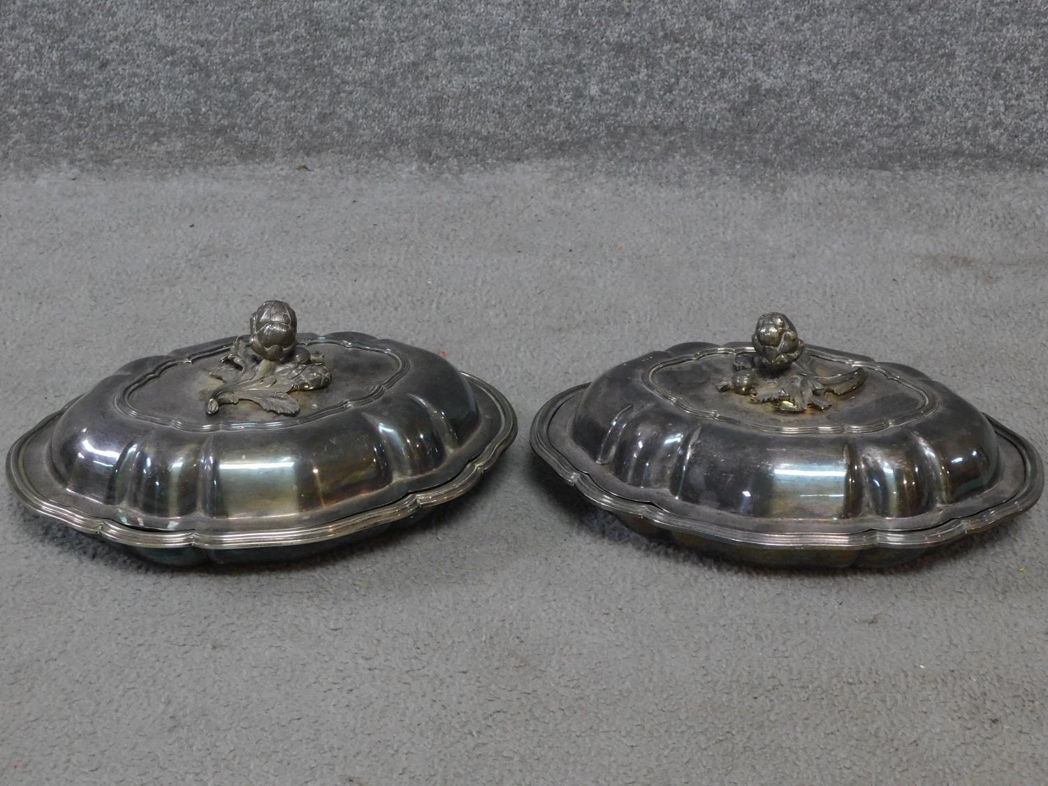 A pair of antique silver plated lidded warming dishes. With floral form and foliate sculpted