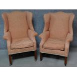 A near pair of Georgian style upholstered wingback armchairs on square section mahogany supports.
