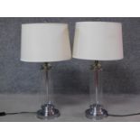 A pair of glass and polished chrome column table lamps with round bases. H.72cm