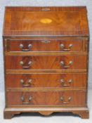 A Georgian style flame mahogany, crossbanded and satinwood inlaid bureau with fitted interior over