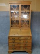 An antique country style pitch pine bureau bookcase with astragal glazed doors above fall front