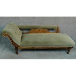 A Victorian beech framed chaise longue decorated with floral carvings and raised on turned supports.