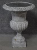 A cast iron garden urn of campana form on block pedestal base. H.76cm