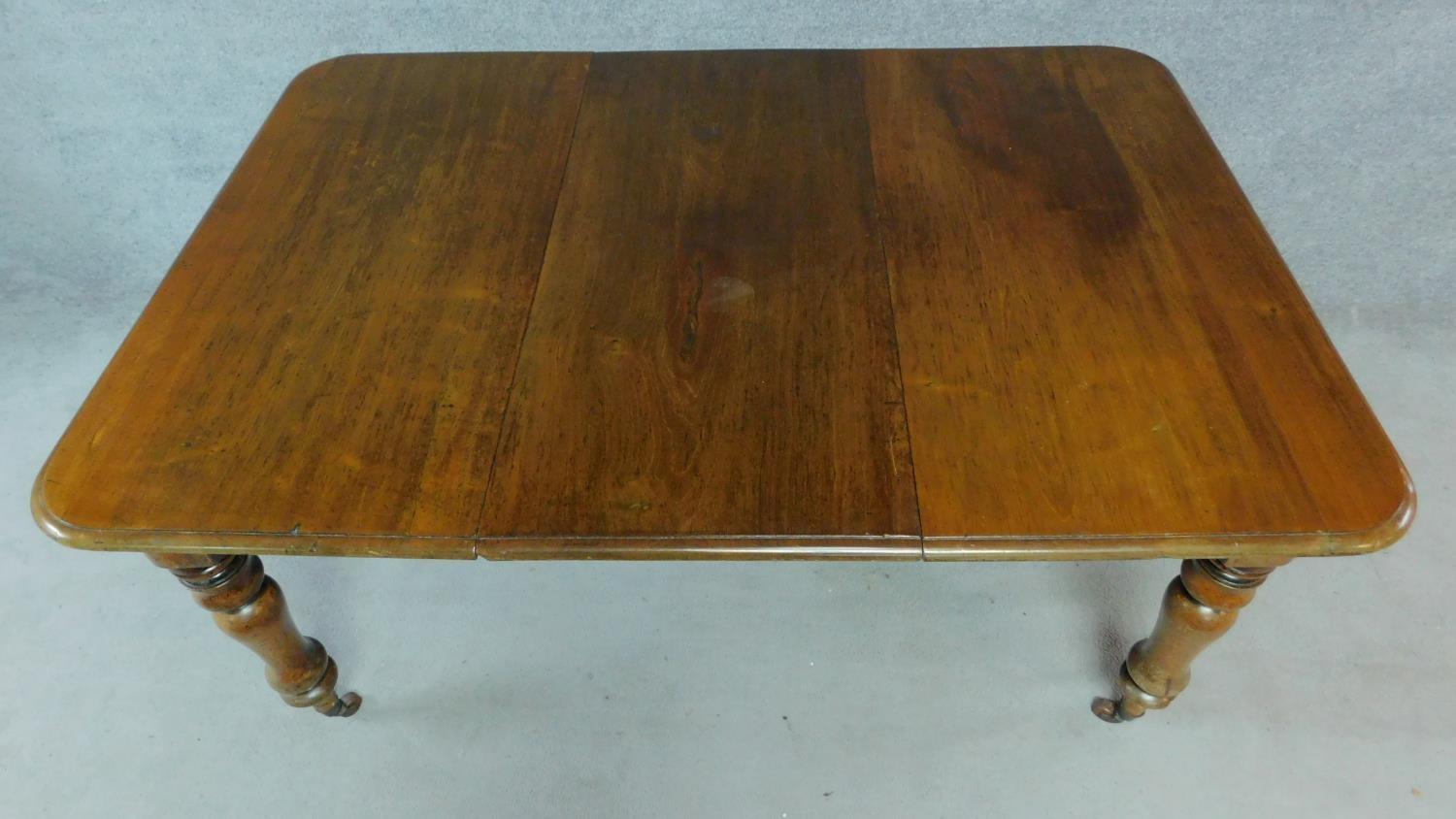 A Victorian mahogany extending table on turned tapering supports terminating on brass cup casters. - Image 2 of 6