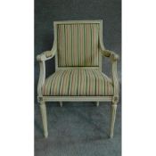 A Louis XVl style painted white armchair in striped upholstery and raised on tapering fluted