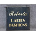 A vintage wall mounted hanging iron sign written 'Roberta ladies fashions'. 60x71cm