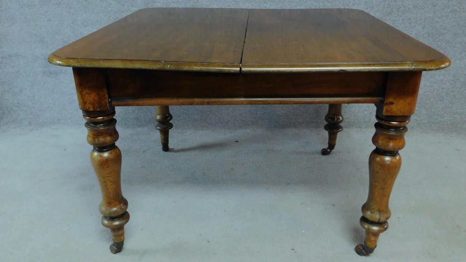 A Victorian mahogany extending table on turned tapering supports terminating on brass cup casters. - Image 4 of 6