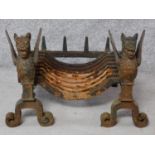 An antique cast iron fire basket flanked by winged griffin andirons. H.40 W.57 D.40cm