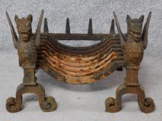 An antique cast iron fire basket flanked by winged griffin andirons. H.40 W.57 D.40cm