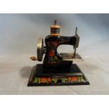 A vintage childs tin plate Casige hand sewing machine with floral detailing and wooden handle and