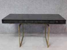 A contemporary designer writing table with ebonised top and four drawers on heavy brass pedestal