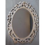 A carved limed oak framed bevelled wall mirror. H.83cm