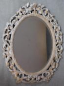 A carved limed oak framed bevelled wall mirror. H.83cm
