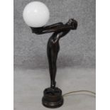 An Art Deco style bronze effect resin table lamp of a lady dancer in a backwards pose with milk