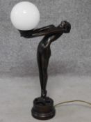 An Art Deco style bronze effect resin table lamp of a lady dancer in a backwards pose with milk