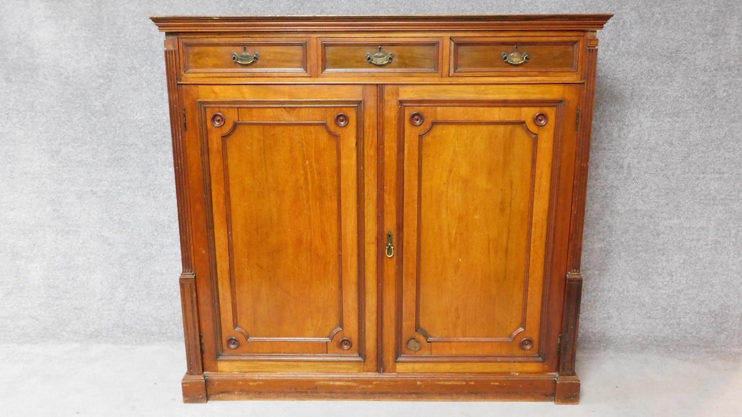 A 19th century mahogany press cupboard with three frieze drawers over panel doors enclosing linen