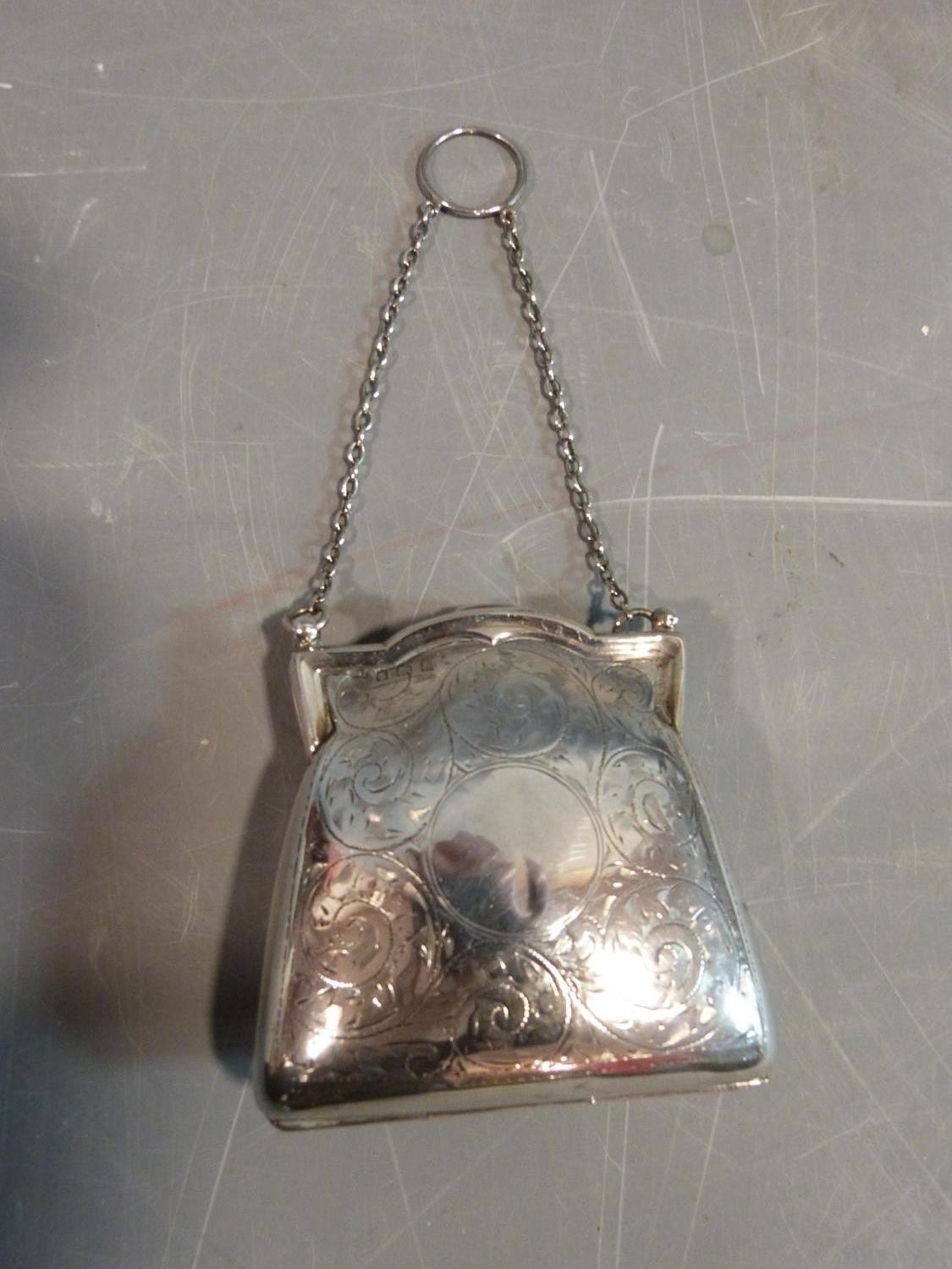 An Edwardian sterling silver ladies coin purse suspended from chain. It has scrolling engraved