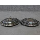 A pair of antique silver plated lidded warming dishes. With floral form and foliate sculpted